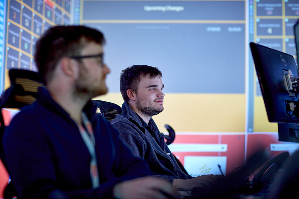 Man sitting at a computer with another man in the foreground