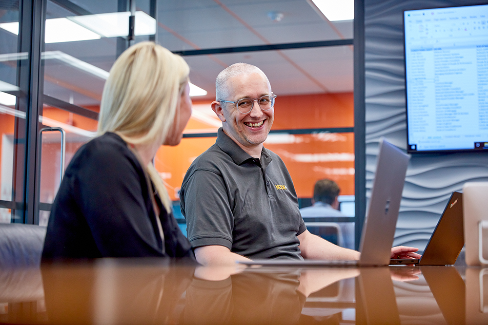 Two people in a meeting sat down smiling