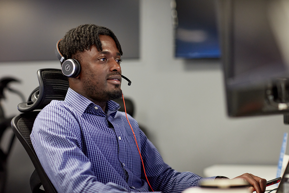 Man sat at computer with headset 1000px